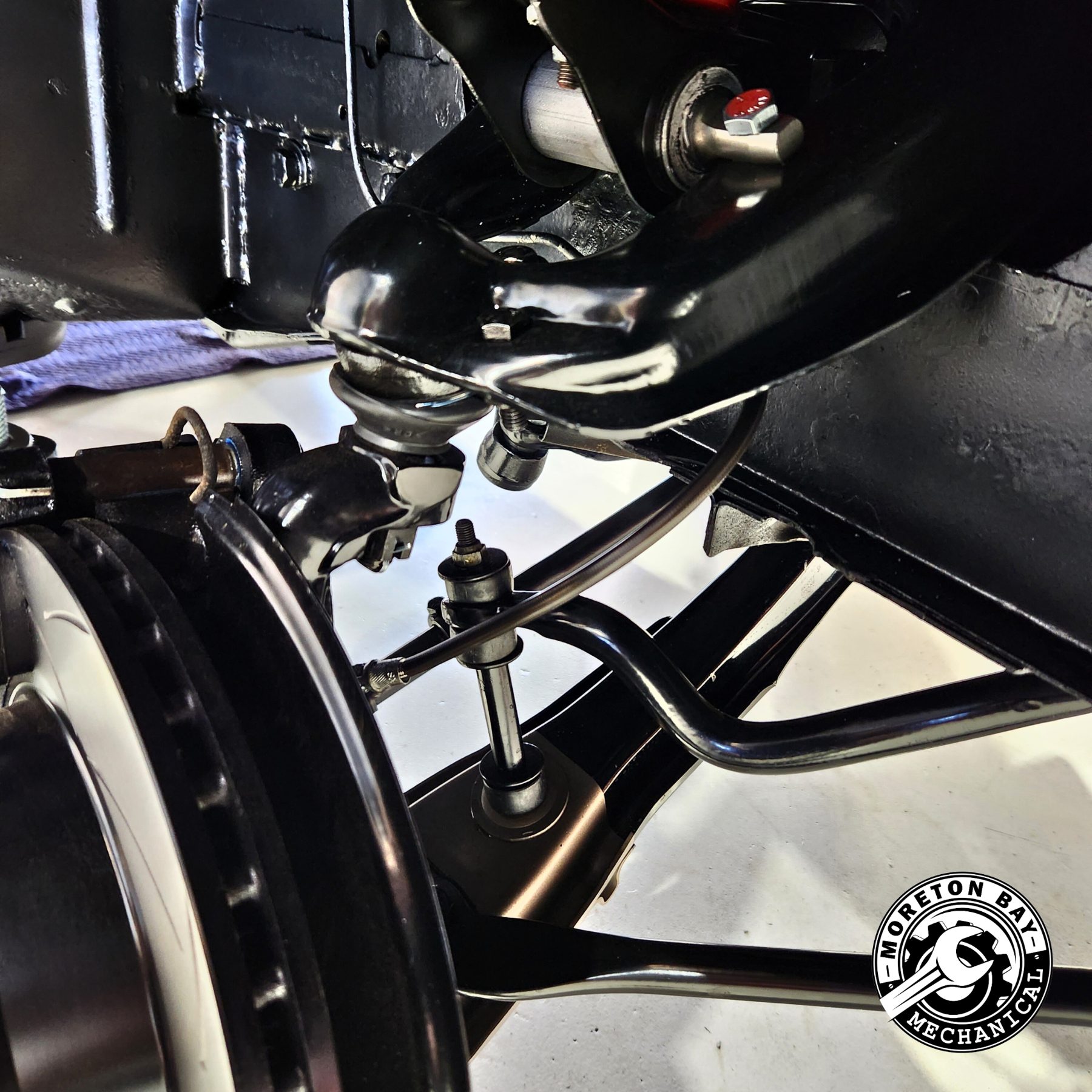 Front suspension and brake work on the underside of a classic car